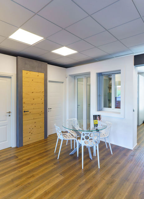 ufficio con tavolo di vetro, quattro sedie bianche, esposizione di porte e infissi finestre