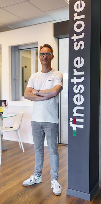titolare del negozio di fianco alla colonna con scritto finestre store